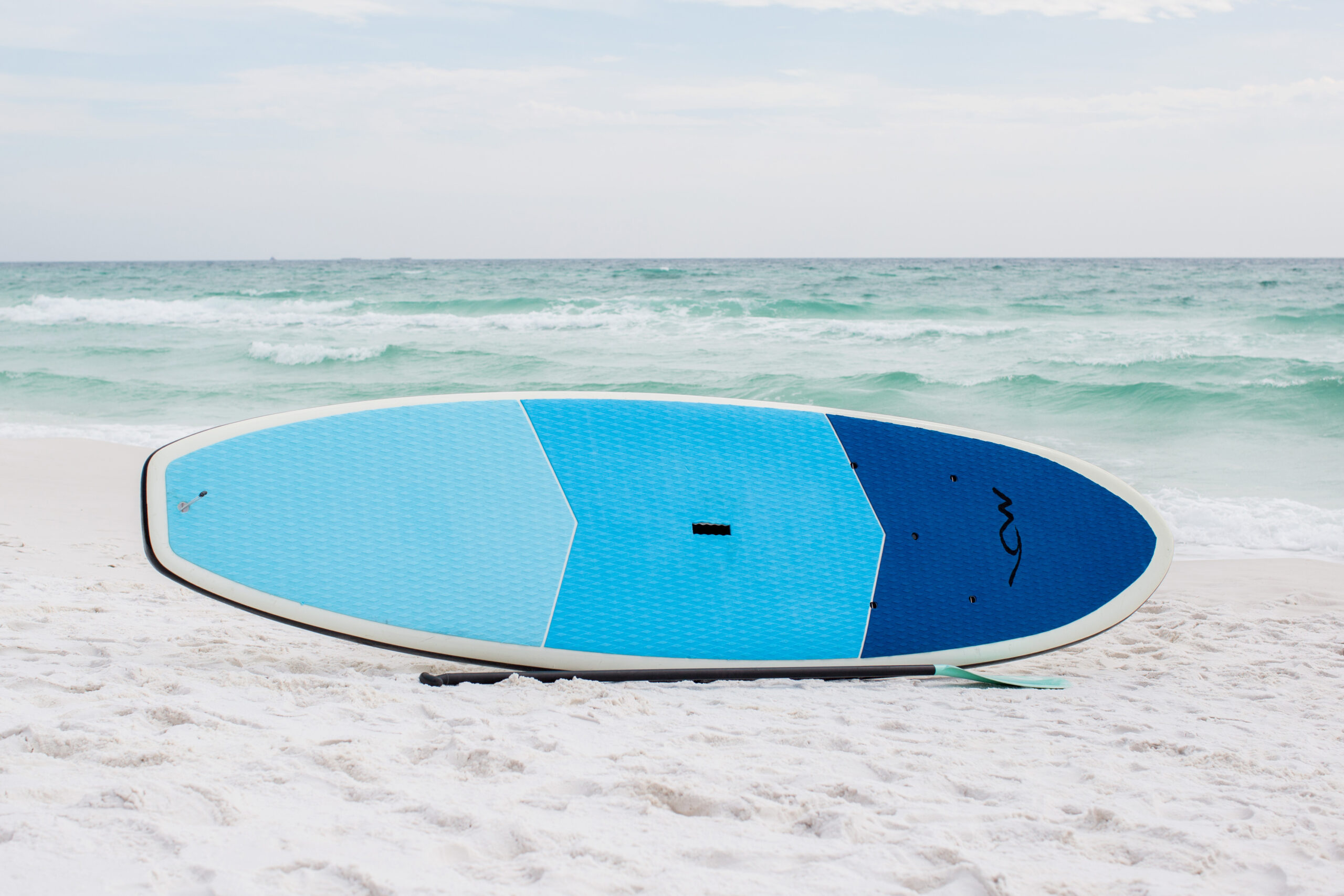 A surfboard sitting on top of the sand near the ocean.