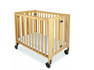 A wooden crib with wheels and white sheets.